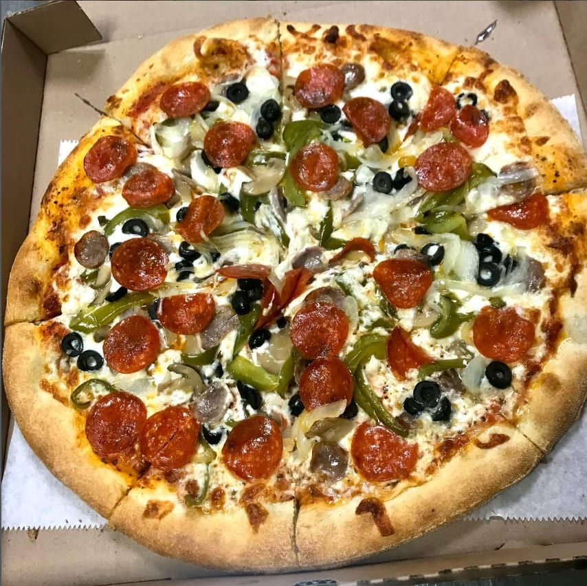 A pepperoni, sausage, pepper and olive pizza in the box